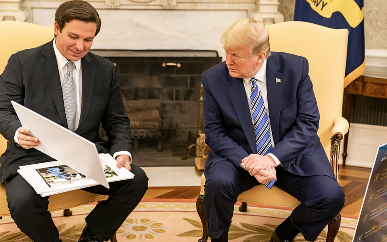 Trump (R) looks at diagrams and photos during his meeting with Ron DeSantis Tuesday, April 28, 2020, in the Oval Office of the White House.
