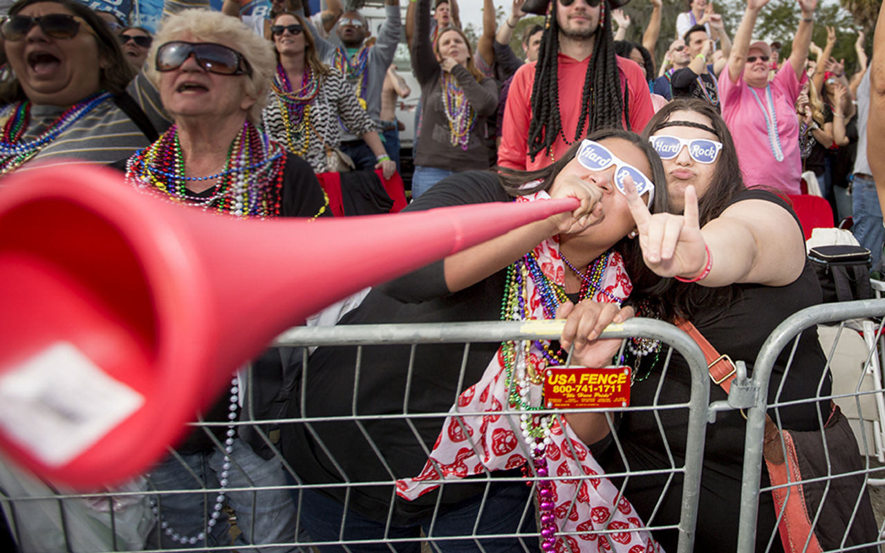 Angelica Mondragon toots her horn for beads while her friend Alexandra Wright rocks on.