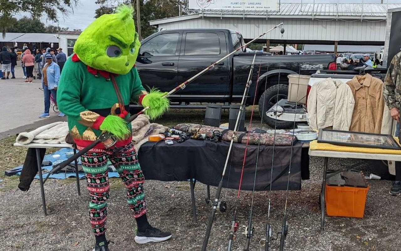 A vendor dressed up as the Grinch shows off some of his wares at the Plant City Farm & Flea Market