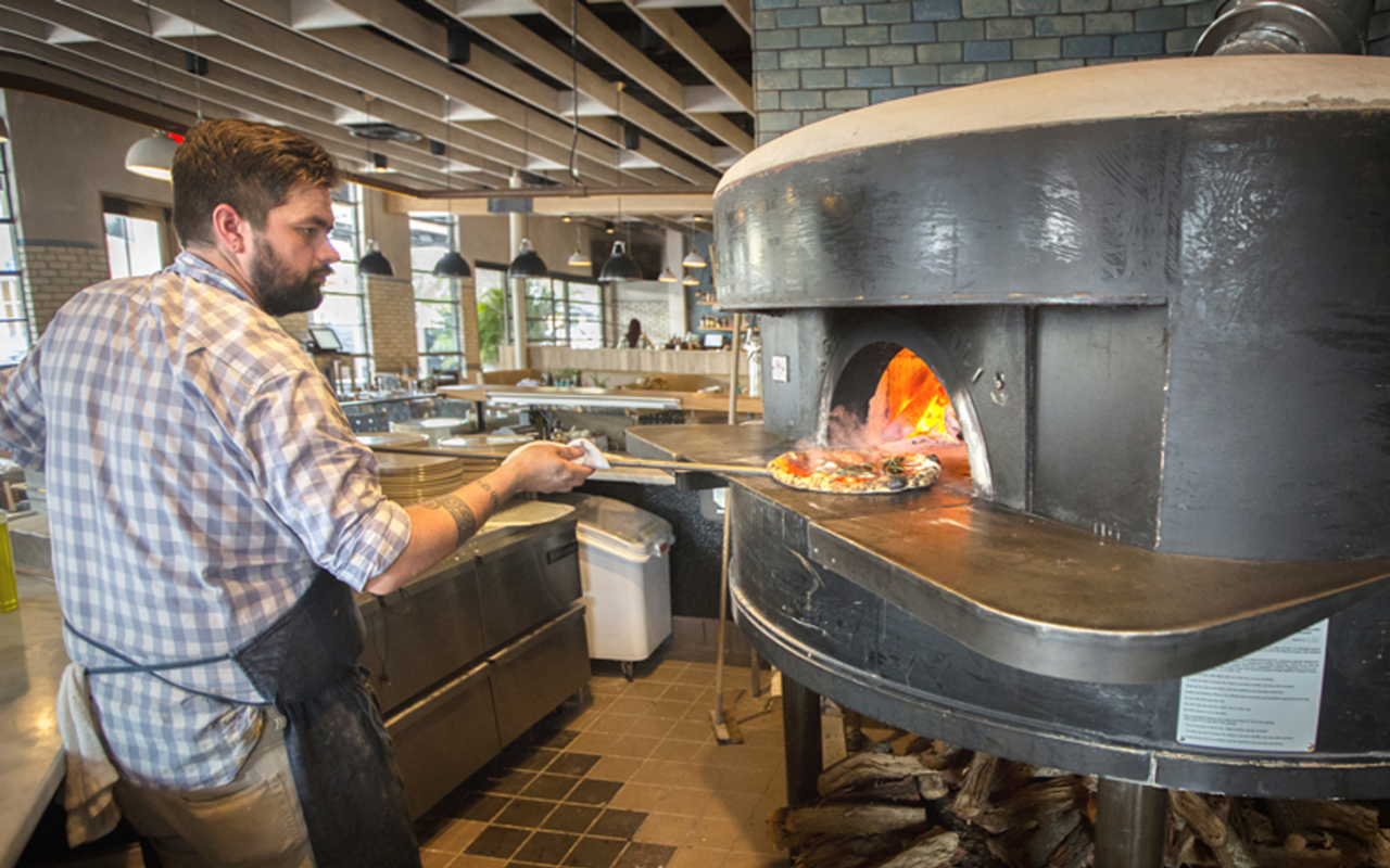 HOT STUFF: Executive chef Josh Hernandez removes a margherita pizza from the Acunto wood-fired oven.