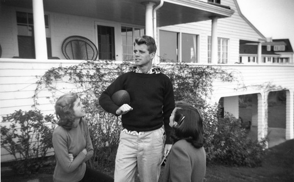 Robert F. Kennedy holds a football in Hyannis Port, Massachusetts with sisters Eunice Kennedy and Jean Kennedy.