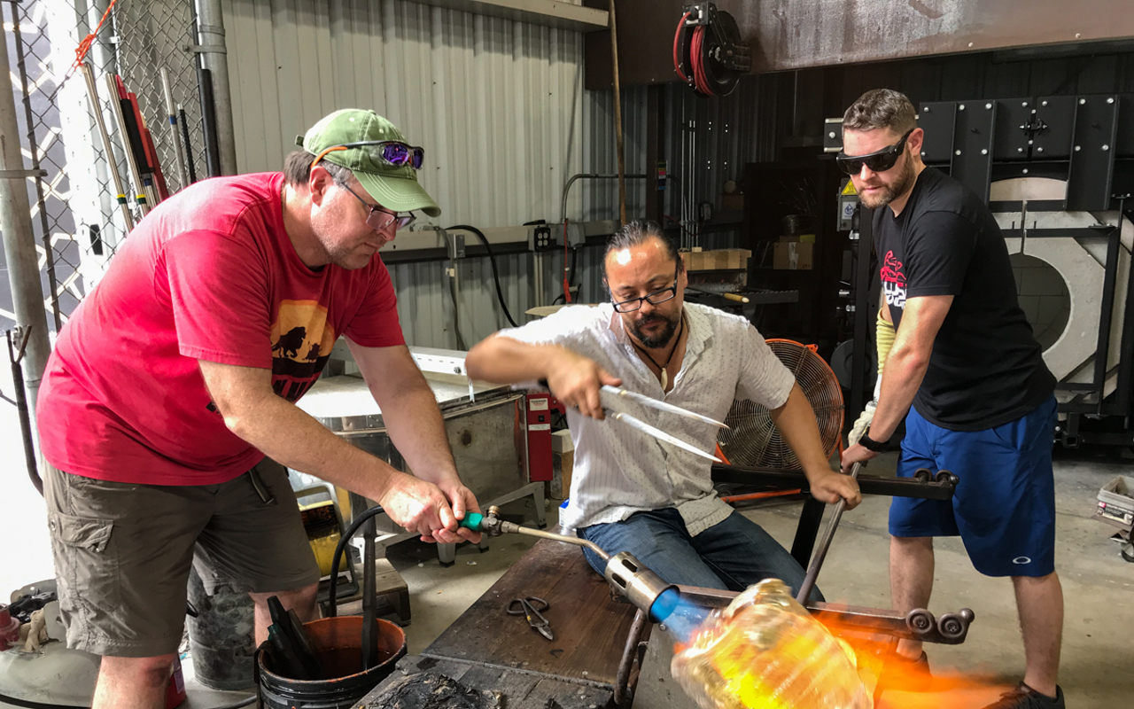 Veterans who participate in Operation Art of Valor at the Morean Hot Shop learn glassblowing. Pictured: Andrew Williamson, Matthew Piepenbrok (Hot Shop manager) and Brian Fernandez.