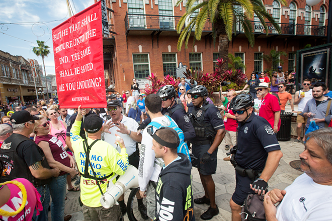 A security guard  for Centro Ybor speaks with Christian protesters while Tampa police officers  look on. - Chip Weiner