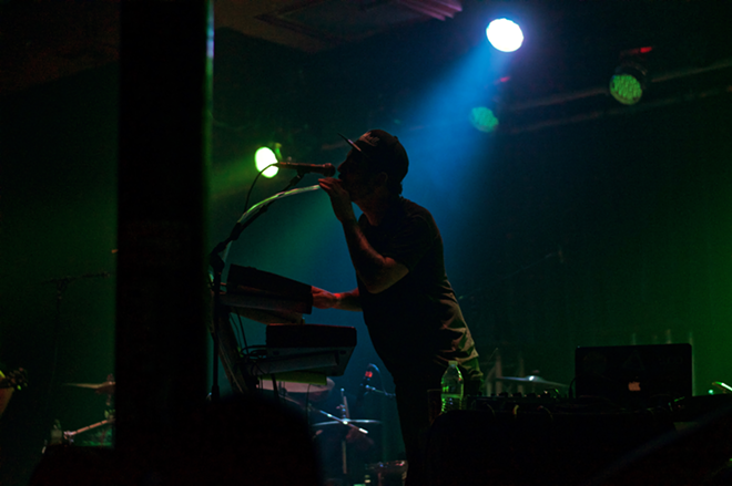 Russ blows into an air controlled portion of his synthesizer on the back-lit stage - Kaylee LoPresto