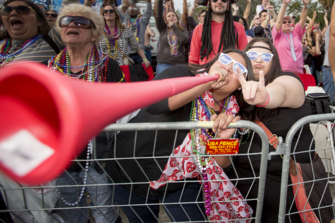 Angelica Mondragon toots her horn for beads while her friend Alexandra Wright rocks on. - Chip Weiner