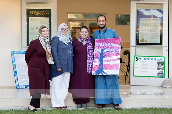 Event organizers Nadia Ismail, Shari Kelley Akram, Alicia D'Amico and Mahmoud Taha Elkasaby stand with a painting gifted to the Islamic Society of Tampa Bay. - Pure Emotions Photography