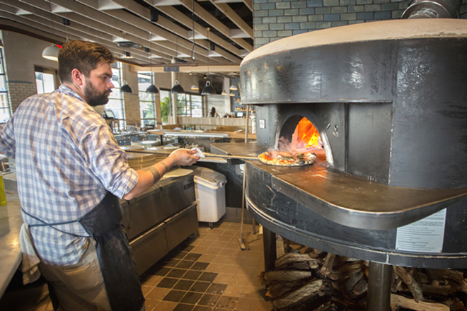 HOT STUFF: Executive chef Josh Hernandez removes a margherita pizza from the Acunto wood-fired oven. - Chip Weiner