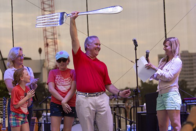 Mayor Buckhorn raises the mac and cheese grand prize trophy while his family looks on. - Chip Weiner