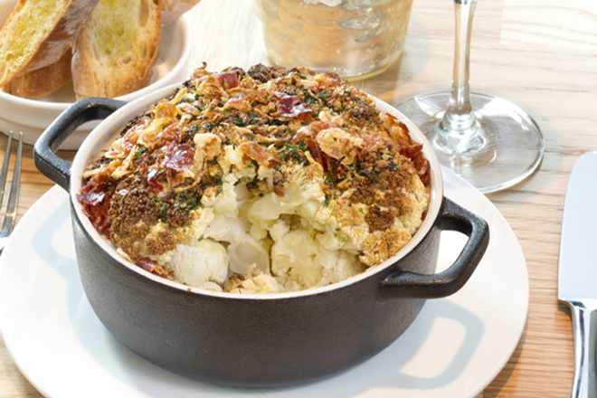 Shallot, ginger and ham top the "Roots & Leaves" whole roasted cauliflower. - Chip Weiner