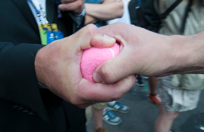 A police officer tries to wrestle a pink tennis ball outside of a Code Pink protester's hand Tuesday evening. - Joeff Davis