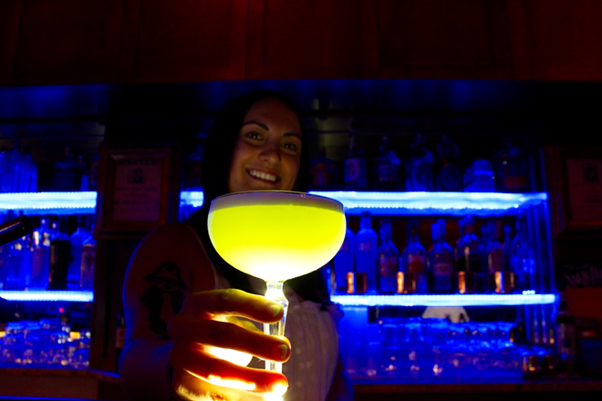 Dolce bartender Sheree King holds her creation, Poisoned Apple, featuring Hendrick's Gin, elderflower liqueur, egg white, lime, apple liqueur and syrup, and flaming Chartreuse. - Laura Mulrooney