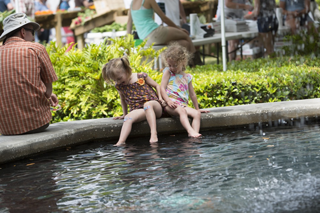 MAKING A SPLASH: Eva, 4, and Carmen, 2, cool off in the fountain while their dad looks on at the Hyde Park Market. - CHIP WEINER