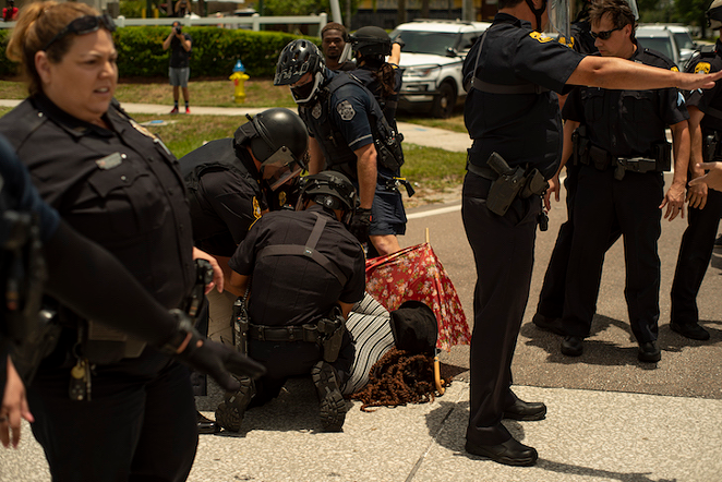 Multiple officers hold Bullock on the ground while arresting her, her face on the hot pavement. - Ashley Dieudonne