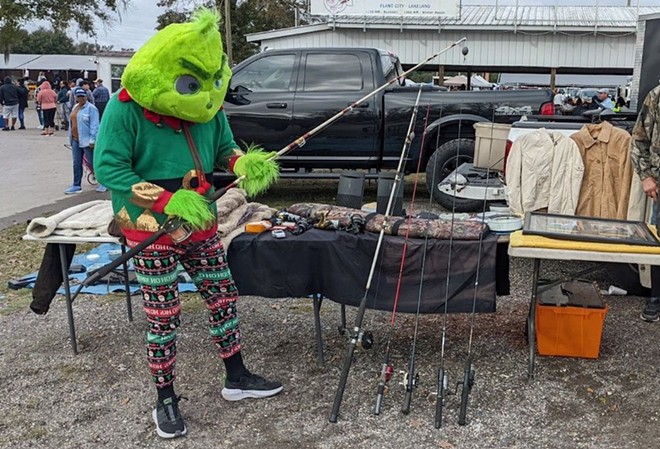 A vendor dressed up as the Grinch shows off some of his wares at the Plant City Farm & Flea Market - Stephanie Allred