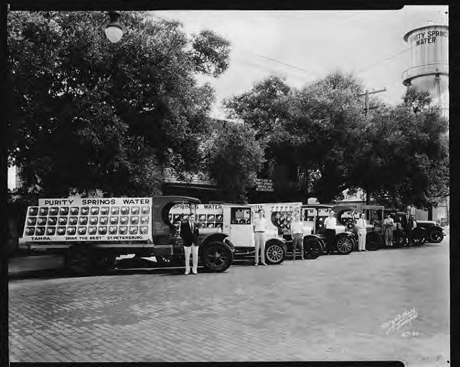 A 1928 Burgert Brothers photograph of men standing by delivery trucks, with the Purity Springs Water Company bottling plant in the background. - Courtesy of Hillsborough County Public Library Cooperative.