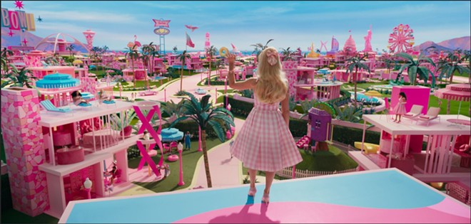 Barbie (Margot Robbie) waves good morning to the residents of Barbieland, a perfectly pink utopia where everyone is equal and capable and appreciated. Gasp! The horror! - Photo via Warner Bros. Pictures