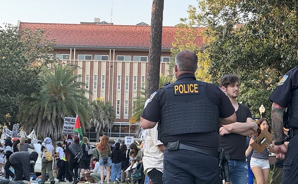 An unidentified University of Florida campus police officer watches over about 50 pro-Palestinian protesters who demonstrated on campus Thursday, April 25, 2024, for a second consecutive day.  There was no violence or police response – a contrast to what was happening at some other college campuses around the U.S.