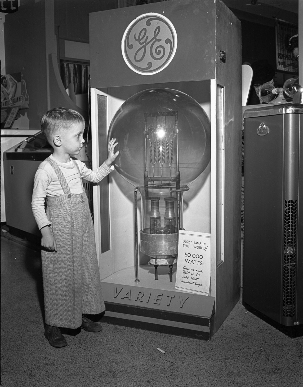 Tommy Dodgen, age 4, standing by the largest lamp in the world, 1947