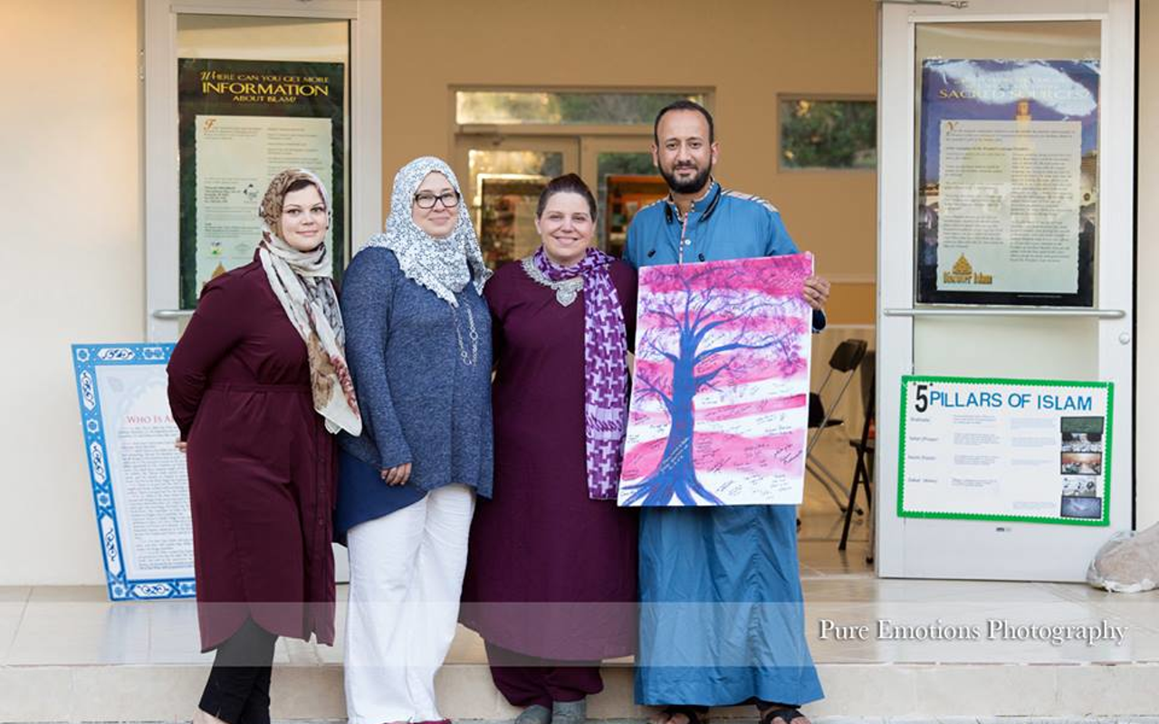 Event organizers Nadia Ismail, Shari Kelley Akram, Alicia D'Amico and Mahmoud Taha Elkasaby stand with a painting gifted to the Islamic Society of Tampa Bay.